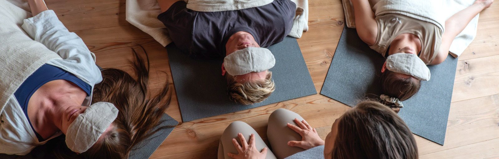 Small group of Yoga Nidra pParticipants resting on the ground with eye pillows