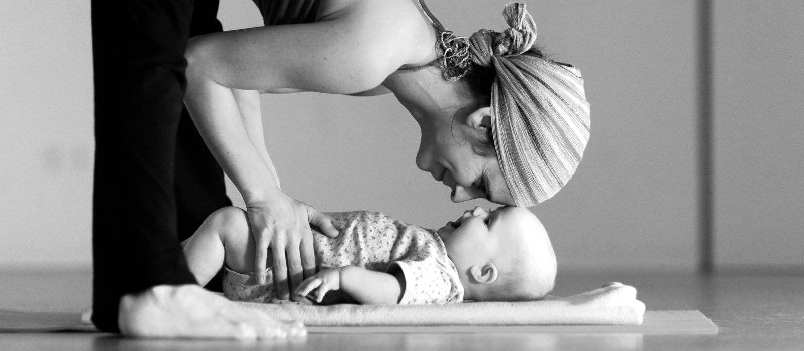 Mother in Prasarita padottanasana head to head with baby daughter (Kira & Maya)